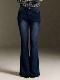 Person wearing blue flared jeans on a neutral background