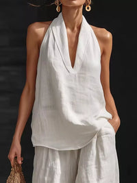 Woman wearing a white halter top and pants against a dark background