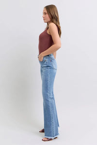 Woman wearing a burgundy top and light blue jeans on a white background