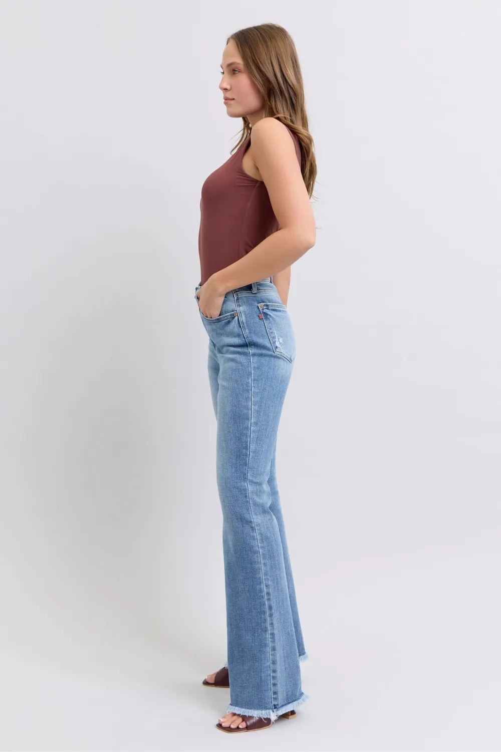 Woman wearing a burgundy top and light blue jeans on a white background