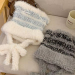 Two textured scarves, one white and blue striped and the other gray, on a light-colored surface.