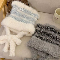 Two textured scarves, one white and blue striped and the other gray, on a light-colored surface.