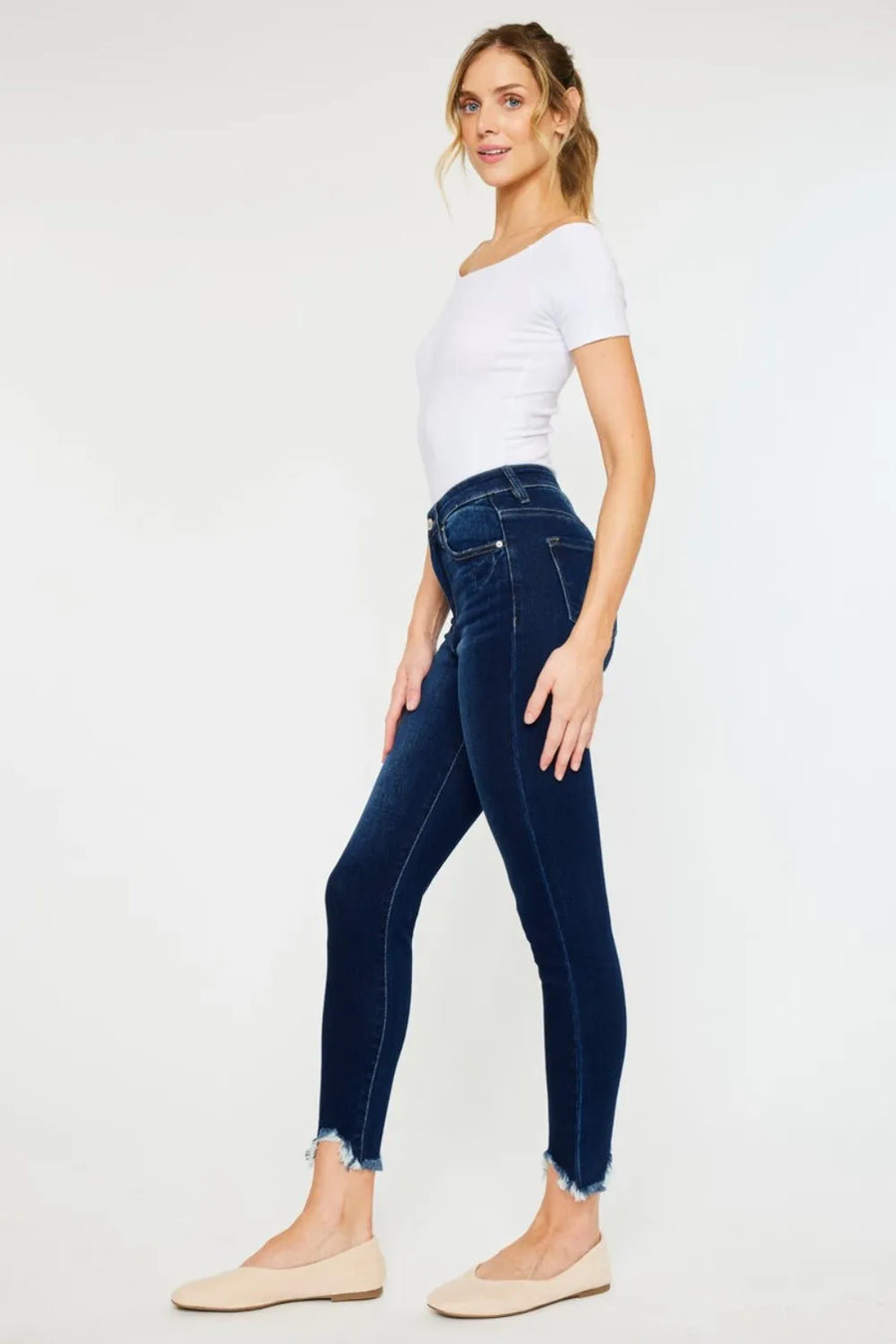 Woman wearing dark blue jeans and a white top on a white background