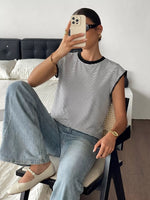 Person taking a mirror selfie wearing a striped shirt and jeans in a bedroom.