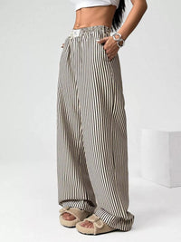 Person wearing black and white striped wide-leg pants on a white background