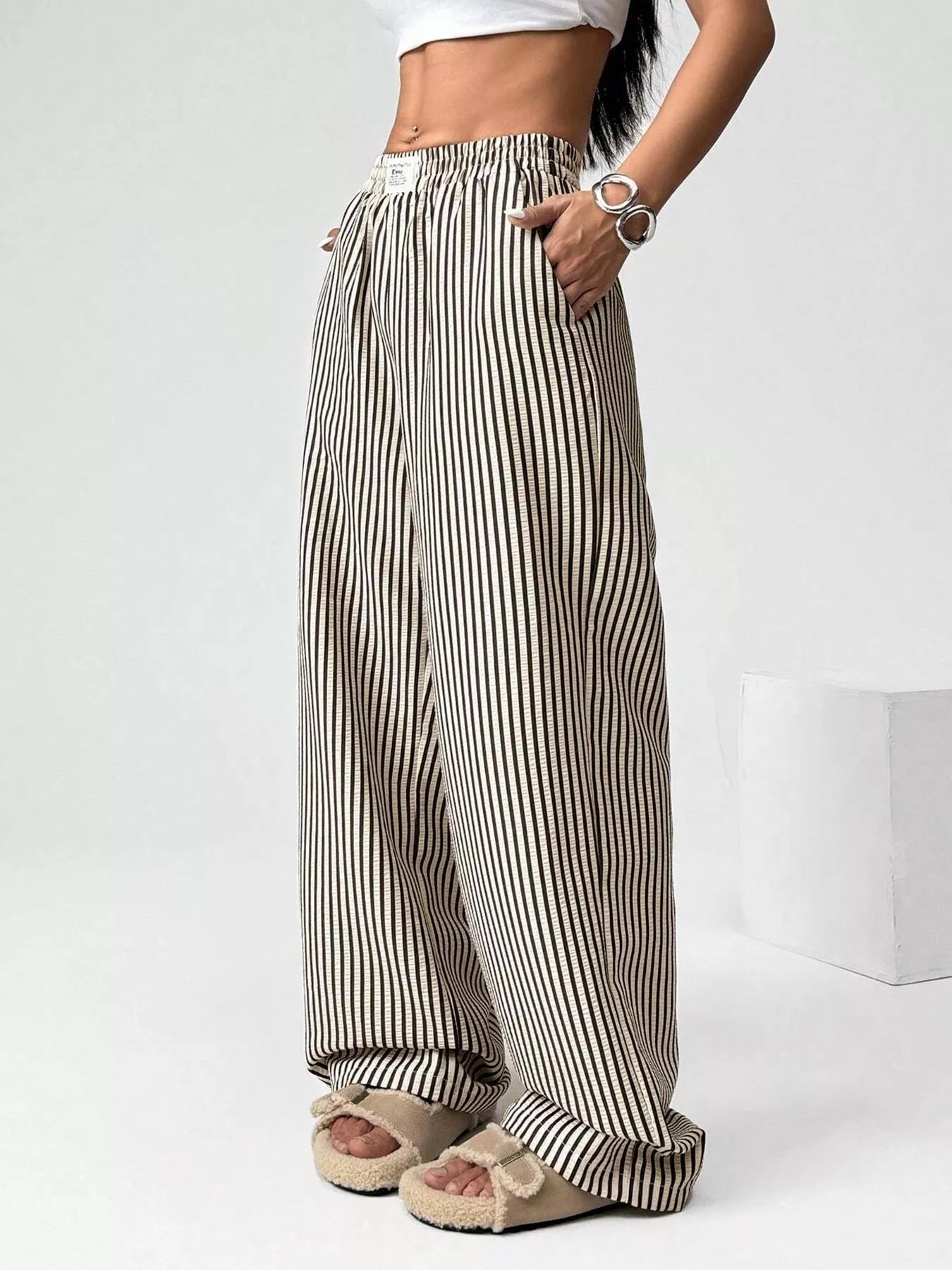Person wearing black and white striped wide-leg pants on a white background