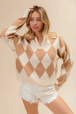 Woman wearing a beige and white argyle sweater with white shorts on a beige background