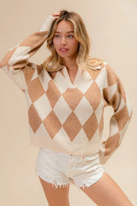 Woman wearing a beige and white argyle sweater with white shorts on a beige background