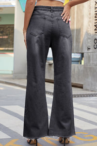 Person wearing black flared jeans standing on a city street.