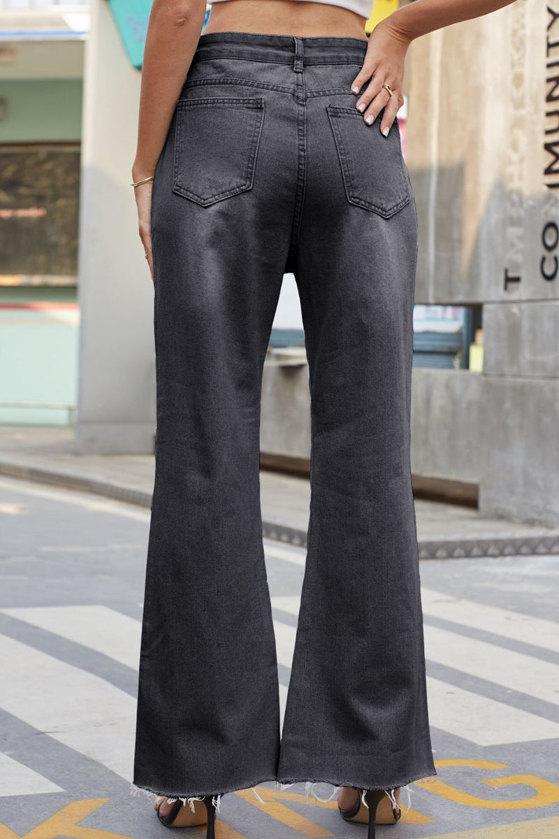 Person wearing black flared jeans standing on a city street.