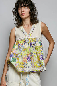 Woman wearing a colorful patchwork top against a gray background