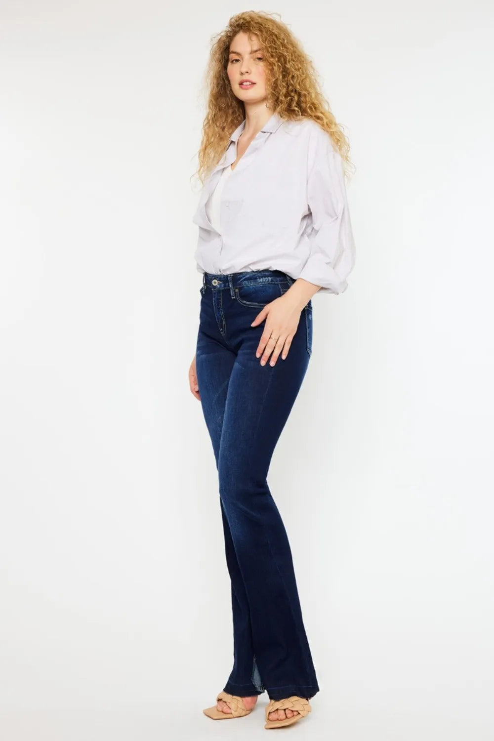 Woman wearing a white blouse and dark blue jeans on a white background