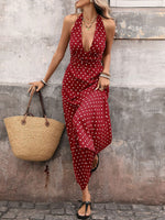 Woman in a red polka dot dress holding a straw bag against a textured wall.