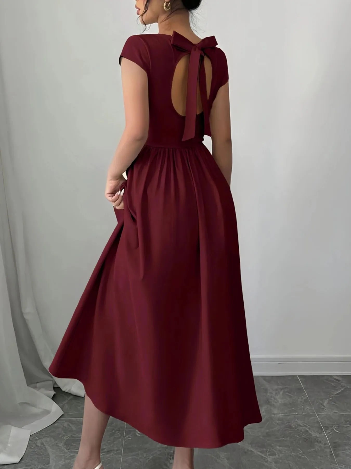 Burgundy dress with cut-out back design on a plain background