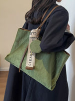 Person holding a green quilted handbag with a visible brand tag.