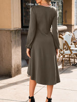 Woman wearing a green dress standing on a sidewalk with outdoor seating in the background.