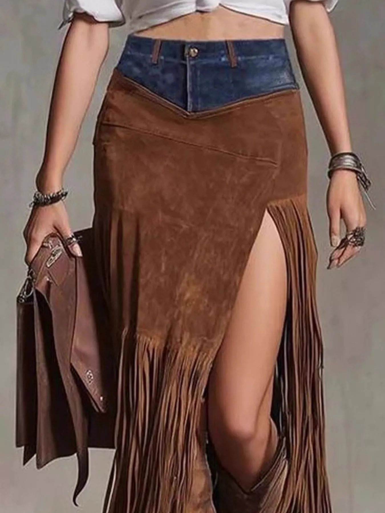 Brown suede fringe skirt with denim top on a neutral background