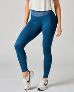 Person wearing blue leggings and white sneakers on a gray background