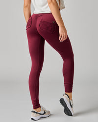 Maroon leggings worn by a person on a gray background