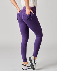 Purple leggings with front pockets worn by a person on a gray background