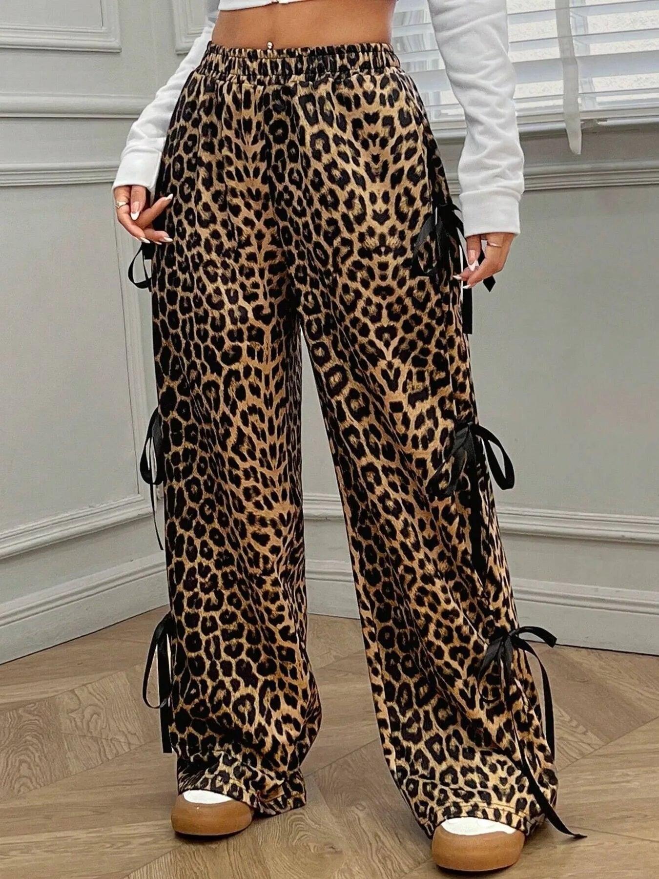 Leopard print pants with black ribbons worn by a person indoors.