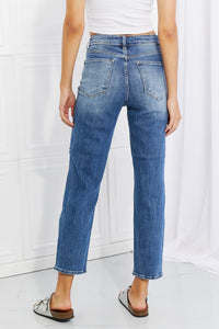 Person wearing blue jeans and a white top against a white background
