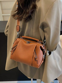 Person wearing a beige coat with a brown leather handbag over the shoulder.