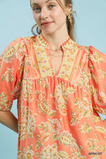 Woman wearing a coral floral dress with a plain background