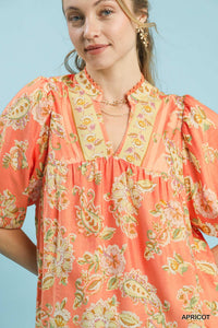 Woman wearing a coral floral dress with a plain background