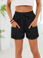 Person wearing black shorts with a white top in a bright room.
