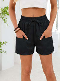 Person wearing black shorts with a white top in a bright room.