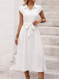 Woman wearing a white dress with a belt on a light background