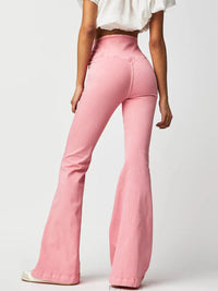 Person wearing pink flared jeans on a white background