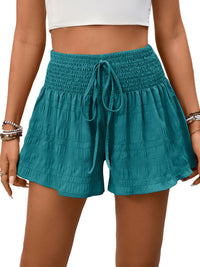Teal shorts with a drawstring waist on a person against a white background
