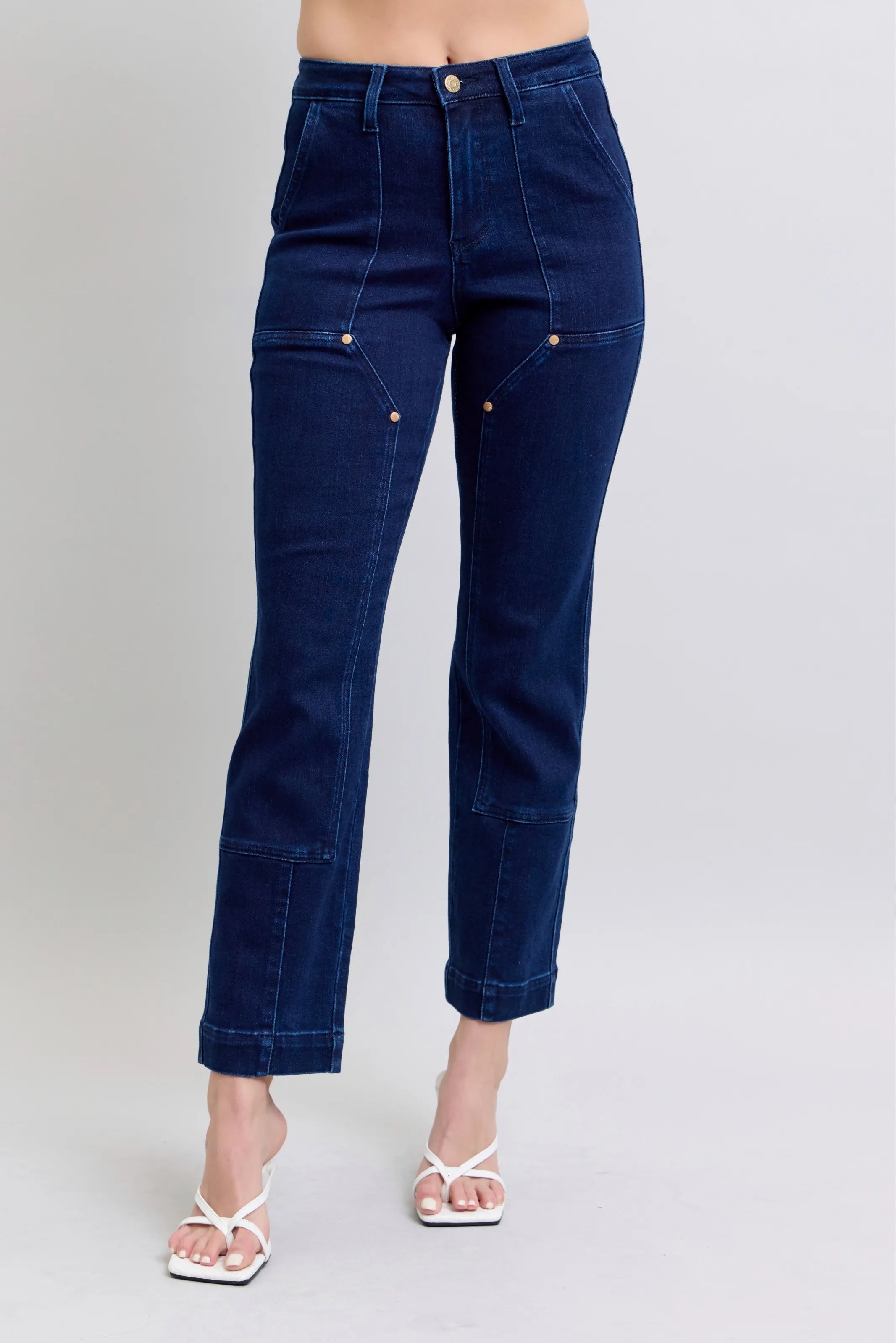 Navy blue jeans worn by a person on a plain background
