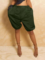 Person wearing green shorts and brown high-heeled shoes on a beige background