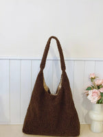 Brown textured handbag on a white surface with a light background