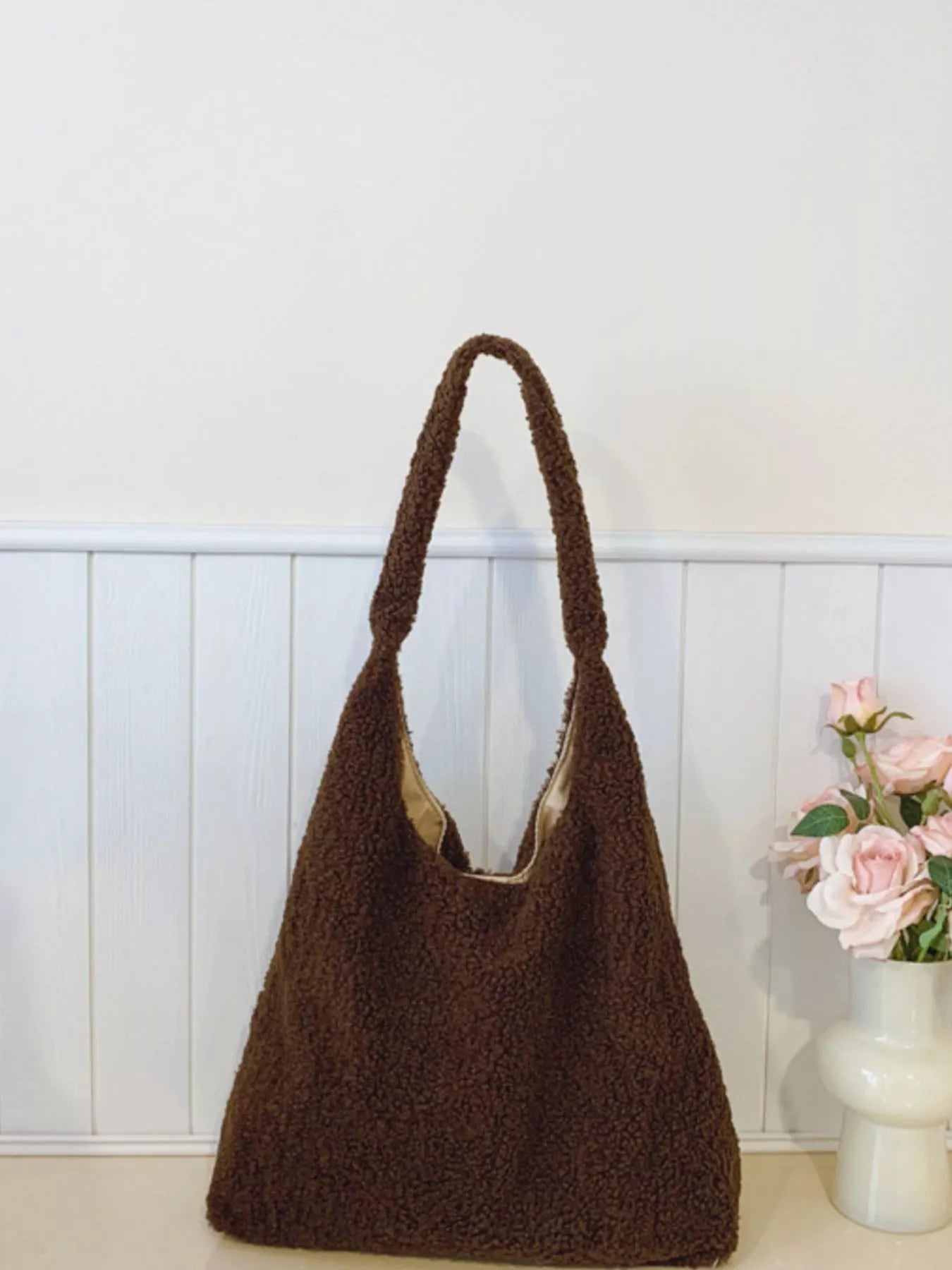 Brown textured handbag on a white surface with a light background