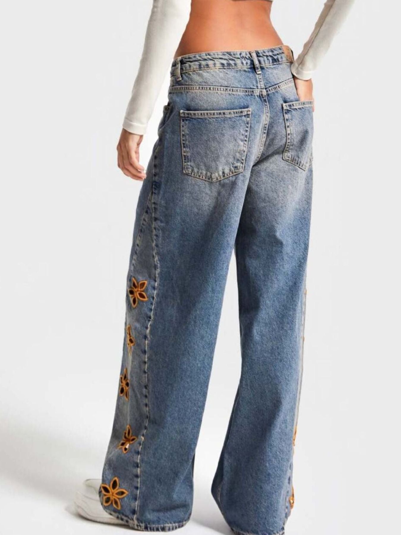 Blue jeans with floral embellishments on a white background