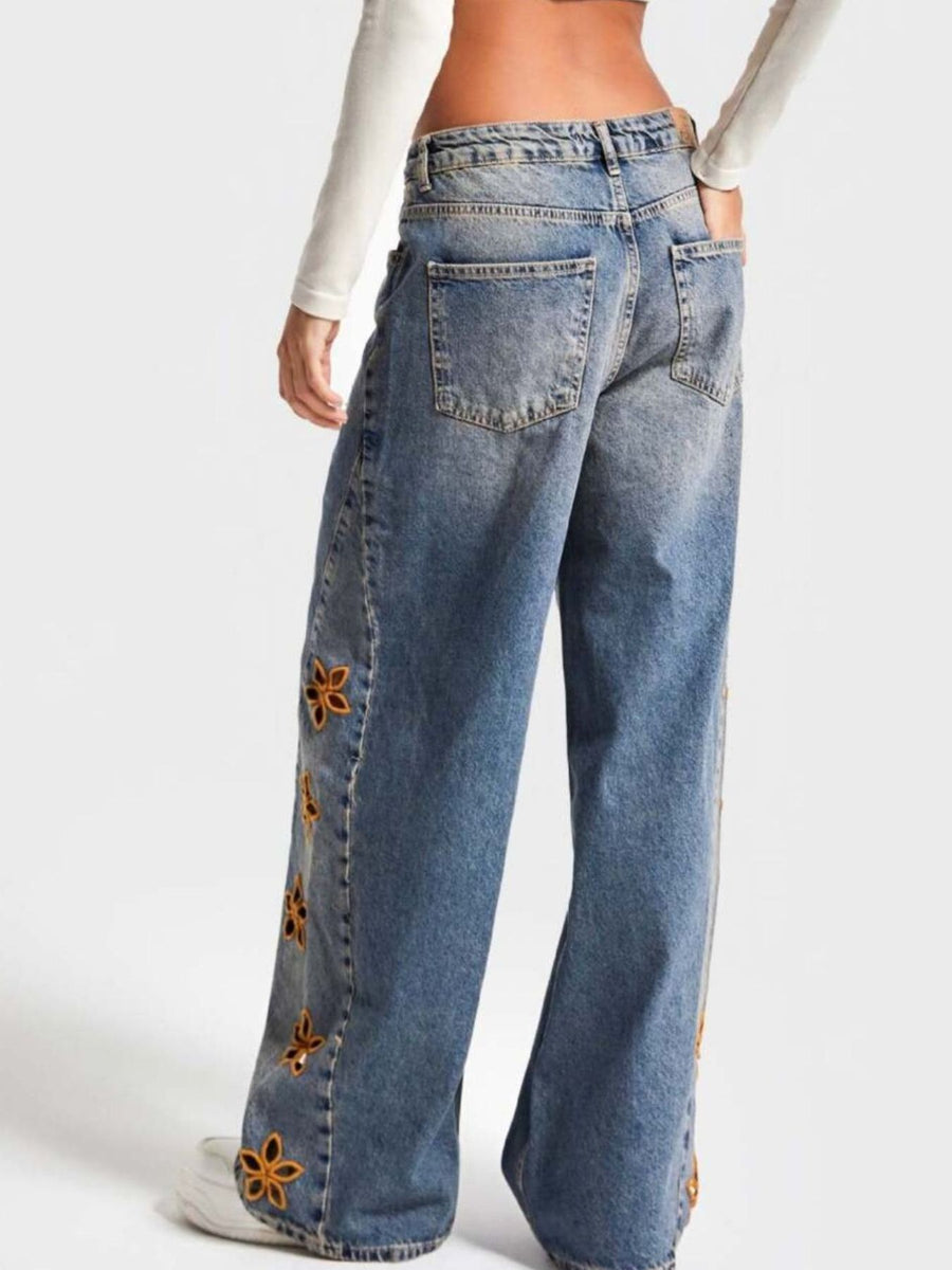 Blue jeans with floral embellishments on a white background