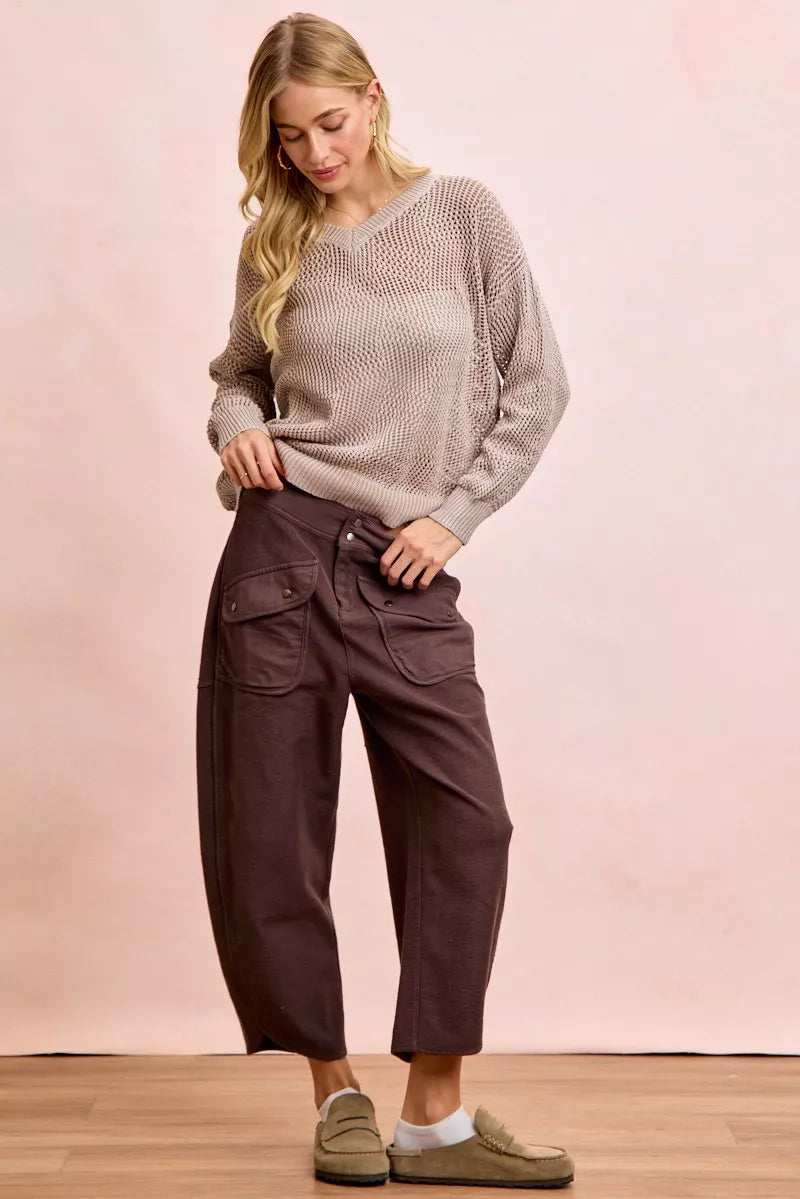 Woman wearing a textured sweater and brown cargo pants against a pink background
