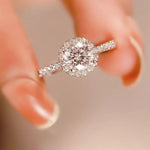 Close-up of a diamond ring held between fingers with a blurred background