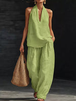 Woman wearing a green outfit holding a woven bag on a dark background