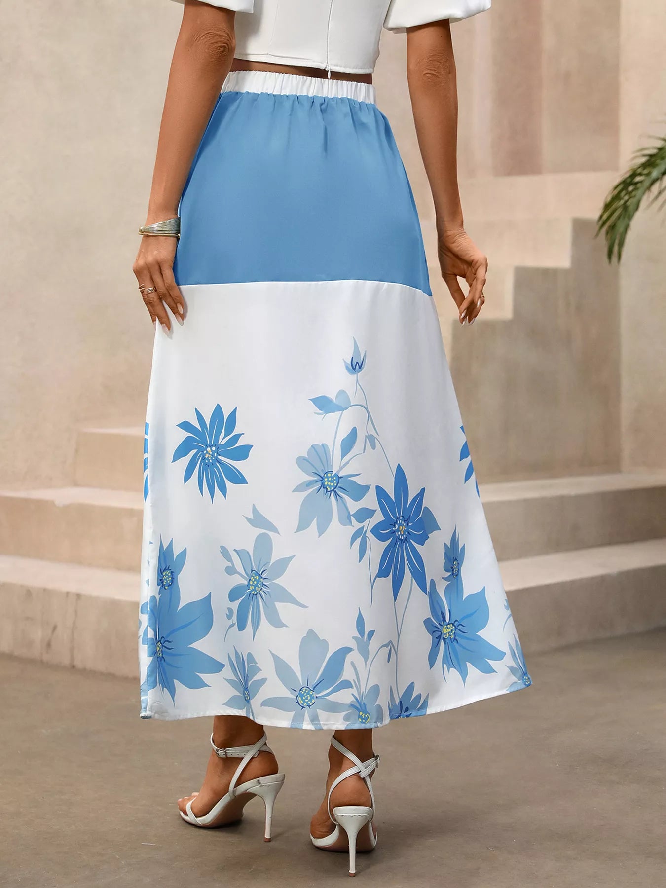 Woman wearing a blue and white floral skirt with a neutral background