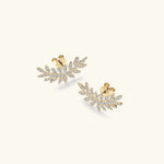 Pair of gold leaf-shaped earrings with embedded stones on a white background
