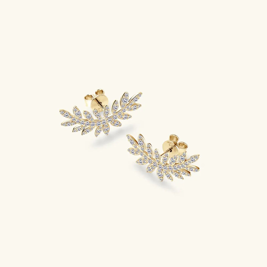 Pair of gold leaf-shaped earrings with embedded stones on a white background