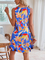 Woman wearing a colorful floral dress in a bright room.