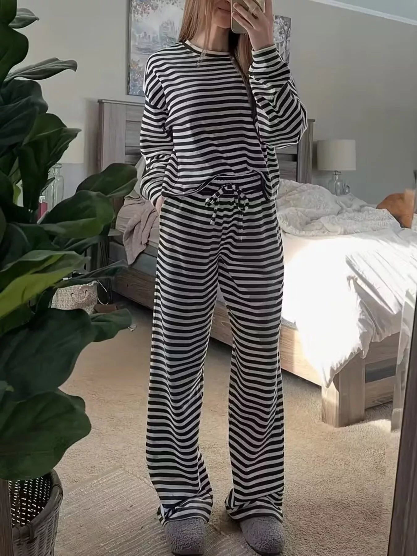Person wearing a black and white striped pajama set in a bedroom.
