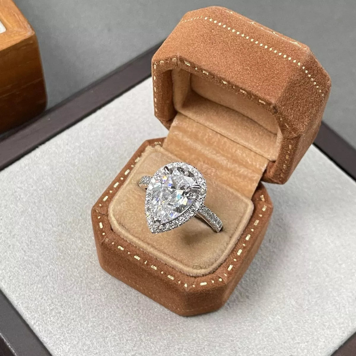Diamond ring in an open brown velvet ring box on a gray surface