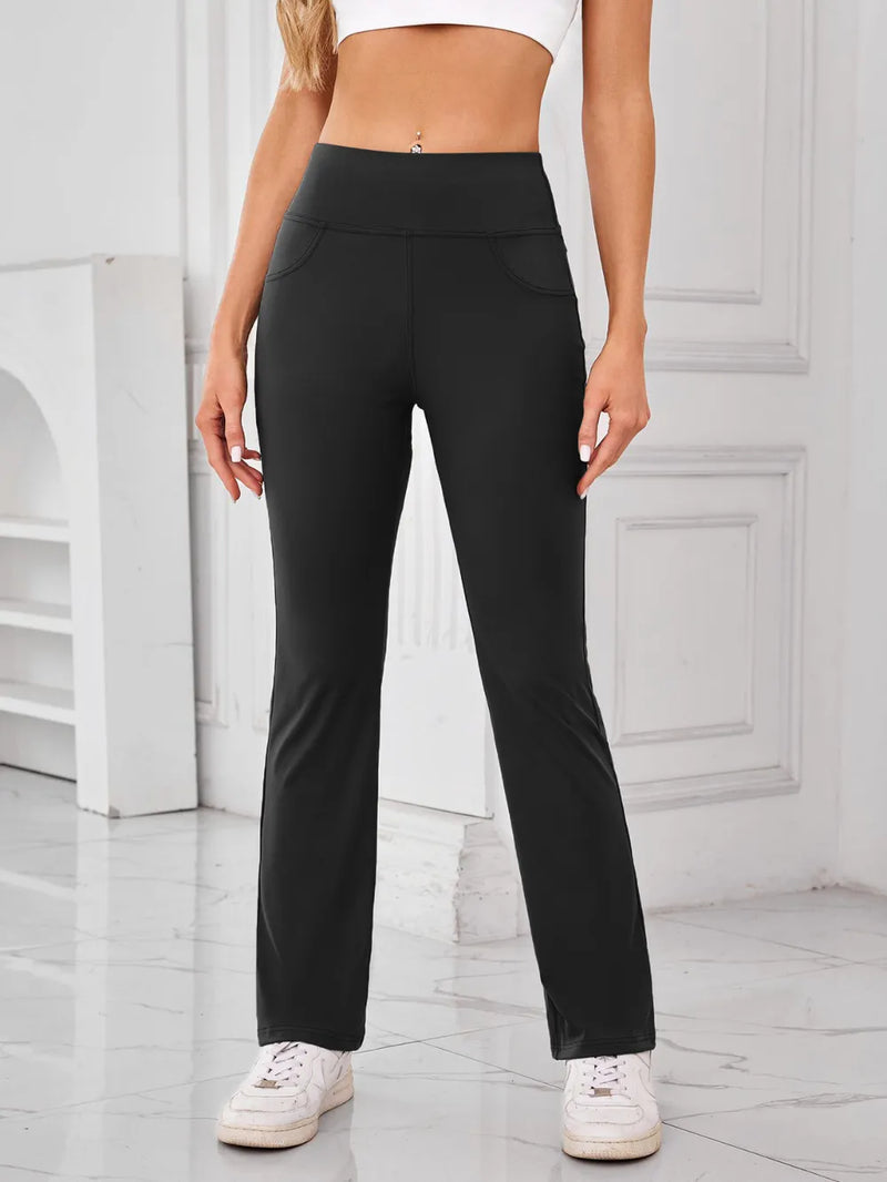 Person wearing black pants and white sneakers in a minimalistic setting